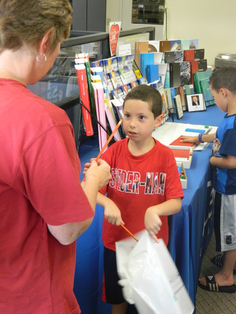 Sindy, from customer service, hands a pencil to one of the students